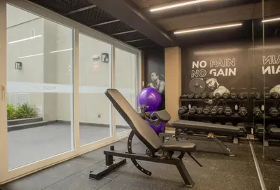a room with a gym with a chair and weights at Sight Oceanview in Barranco Malecon by Wynwood House in Lima