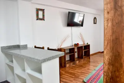 a kitchen with a counter and a tv on the wall at Apart Hotel El Puma in Cusco