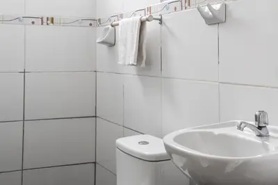 a white bathroom with a toilet and a sink at Apart Hotel El Puma in Cusco