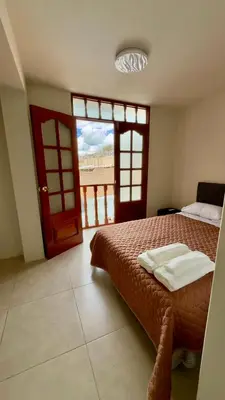 a bedroom with a bed and a door with a view at Habitación con Balcón Castellares La Puebla in Ayacucho