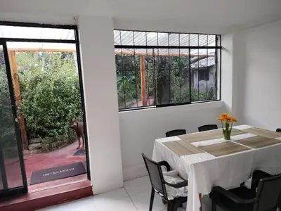a white dining room with a table and a window at Casa Jardin in Ayacucho