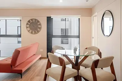 a dining room with a glass table and chairs and a clock at Edificio Vital in Lima