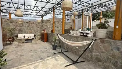 a patio with a hammock on a stone wall at Casa campo vista linda in Mala