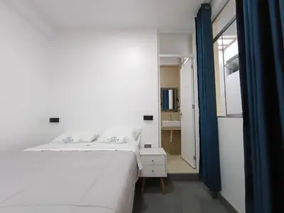 a bedroom with a large white bed and a bathroom at Hospedaje Altamar in Paracas
