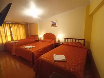 a hotel room with two beds with red sheets at Hostal Cusco Inn in Cusco