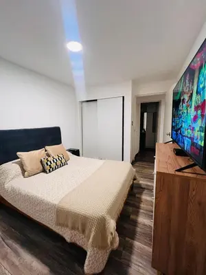 a bedroom with a large bed and a flat screen tv at Monterrico Polo Aparts #3 - Dpto con AC a una cuadra Embajada de USA in Lima