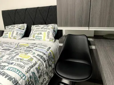 a black chair sitting next to a bed in a room at Wake Up Near The Sea in Lima