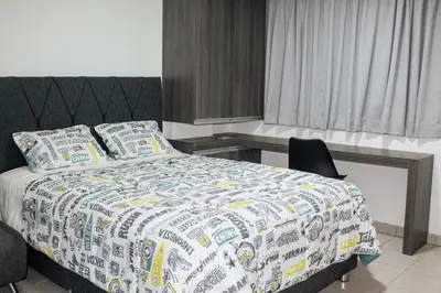 a bedroom with a large bed with a desk and a bed sidx sidx at Wake Up Near The Sea in Lima