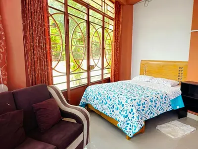 a bedroom with a bed and a couch and a window at Familiar 1er piso in La Merced