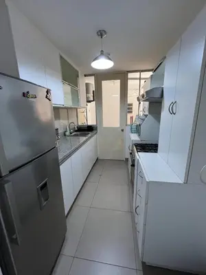 a kitchen with white cabinets and a stainless steel refrigerator at Departamento con balcon y vista al mar in Lima