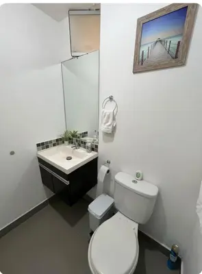 a white bathroom with a toilet and a sink at Departamento con balcon y vista al mar in Lima