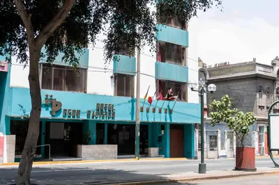 a blue building on a city street with a tree at Hotel Perú Pacífico in Lima