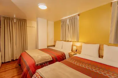 two beds in a hotel room with yellow walls at Kamma Guest House in Ollantaytambo