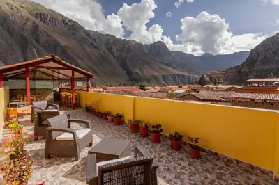 a patio with chairs and tables and mountains in the background at Kamma Guest House in Ollantaytambo
