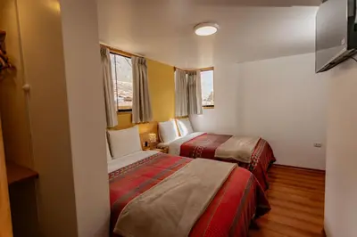 a hotel room with two beds and two windows at Kamma Guest House in Ollantaytambo