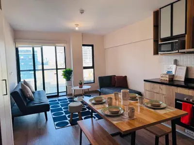 a living room with a table and a couch and a kitchen at Monterrico Polo Aparts 19 - Dpto de Estreno con Balcon frente Embajada USA in Lima
