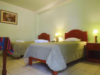 a hotel room with two beds and two lamps at Libon's Hotel in Nazca