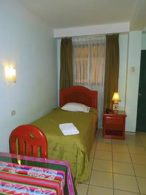 a bedroom with a bed and two red chairs at Libon's Hotel in Nazca