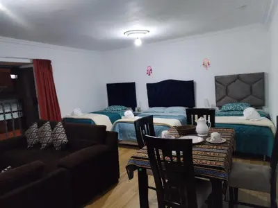 a room with two beds and a table and a couch at Guadita House in Cusco