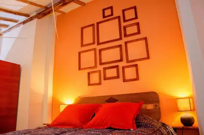 a bedroom with an orange wall with a bed with red pillows at Historical Center Apartments in Cusco