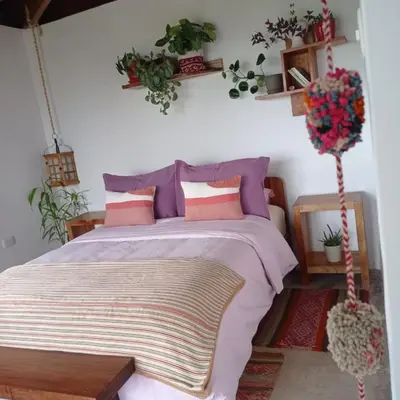 a bedroom with a bed with purple and pink pillows at Chunchu Wasi All included