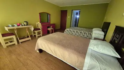 a hotel room with two beds and a table and a mirror at Dormitorio con baño privado a 25 minutos del Apto in Lima