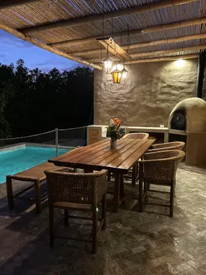 a wooden table and chairs on a patio with a pool at Casa de Campo con Piscina, BBQ y Naturaleza Cañete in Imperial