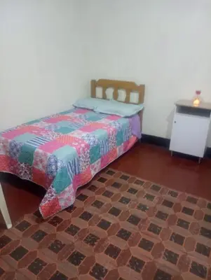 a bedroom with a bed and a table at Habitación Plaza Chosica in Chosica