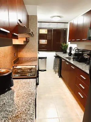 a kitchen with wooden cabinets and granite counter tops at Departamento en Miraflores - Av Pardo Jose in Lima