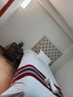 a bedroom with a large bed with white sheets at Hotel Inka House Chinchero in Chinchero