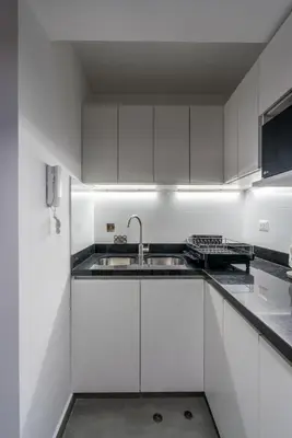 a white kitchen with white cabinets and a sink at Nuvee 2BR by Geko in Lima
