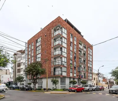 a brick building with cars parked in a parking lot at Nuvee 2BR by Geko in Lima