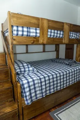 a wooden bunk bed with a blue and white checkered mattress at Casa en el Medio de todo Estacion tren Angamos in Lima