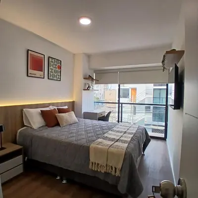 a bedroom with a bed and a large window at Vive Barranco, Reserva aquí in Lima
