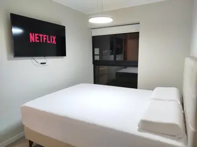 a white bed in a room with a tv on the wall at Apartamento de ensueño in Lima