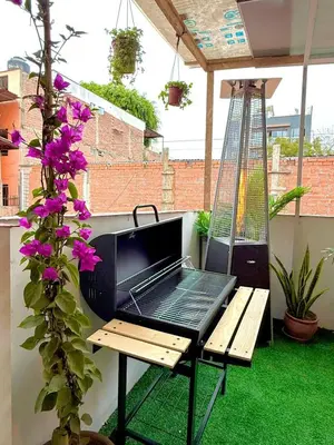 a barbecue grill on a balcony with purple flowers at Lima Hostel - Barranco in Lima