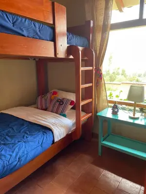 a bunk bed with a ladder next to a table at Charming Urubamba Cusco house - Kapuliyuq in Urubamba