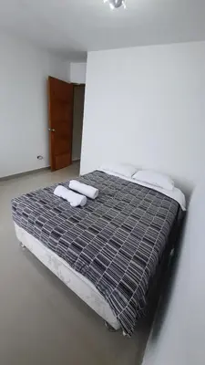 a bed in a white room with towels on it at HABITACIÓN PRIVADA En Casa a 13 minutos Acceso A Baño, Cocina Y Comedor Compartido in Lima