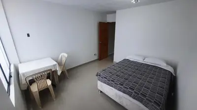 a bedroom with a bed and a table and chairs at HABITACIÓN PRIVADA En Casa a 13 minutos Acceso A Baño, Cocina Y Comedor Compartido in Lima
