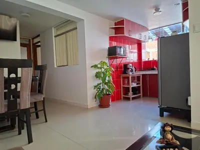 a kitchen with red cabinets and a table in a room at Cusco Hermoso in Cusco