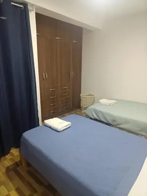 a bedroom with two beds and a closet with towels on top at Departamento Frente al Cc Mega plaza - Ica in Ica