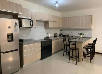 a kitchen with stainless steel appliances and wooden cabinets at Los Tambos Apartment in Cusco