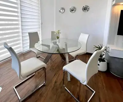 a dining room with a glass table and white chairs at La Panaca Del Inka Apartment in Cusco