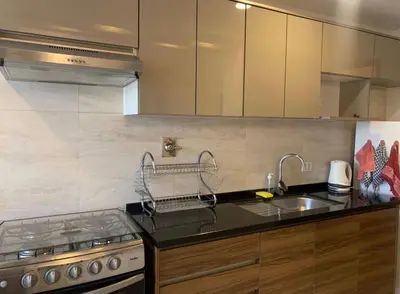 a kitchen with a sink and a stove and cabinets at Qori Apartment in Cusco