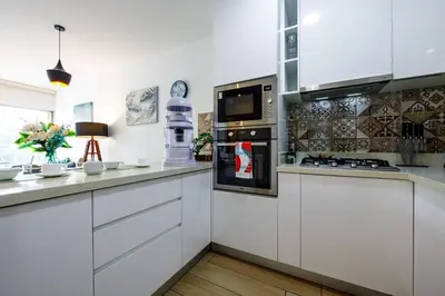 a kitchen with white cabinets and a stove top oven at BSR Romantic Escape Flat w/ Rooftop Pool in Lima
