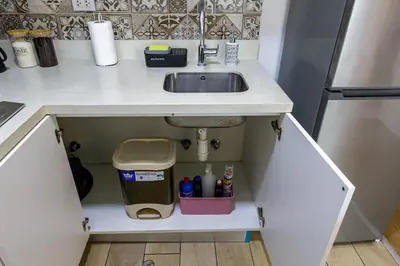 a kitchen counter with a sink and a trash can at BSR Romantic Escape Flat w/ Rooftop Pool in Lima