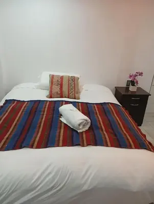 a bed with a striped blanket and a pillow on it at Si buscas un lugar para tu familia in Cusco