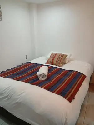 a white bed with a colorful blanket and pillows on it at Si buscas un lugar para tu familia in Cusco