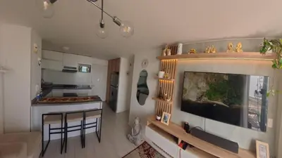 a living room with a large television and a kitchen at Ocean Blue, Vista Frontal Al Mar in Lima
