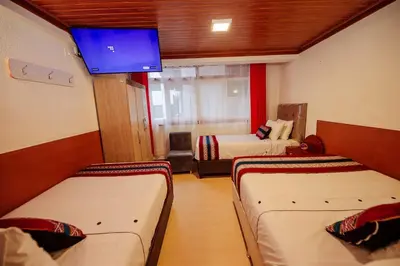 a room with two beds and a flat screen tv at Avraham Hotels in Machu Picchu
